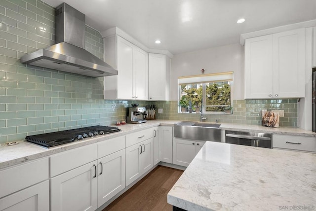 kitchen with tasteful backsplash, white cabinets, stainless steel appliances, dark wood-type flooring, and wall chimney exhaust hood