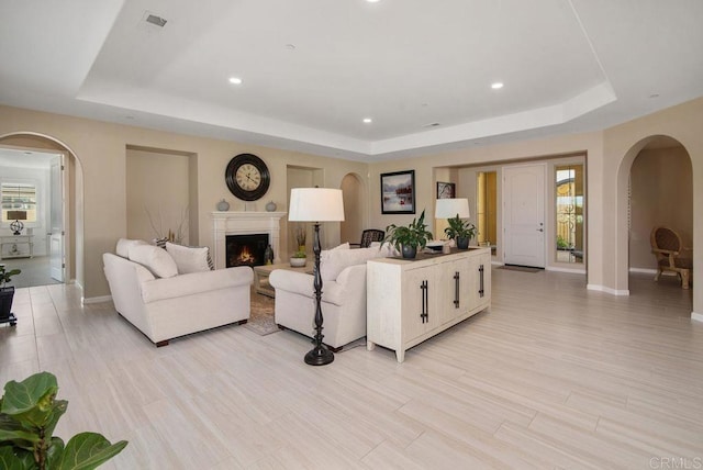 living room with a raised ceiling and light wood-type flooring