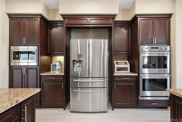 kitchen with stainless steel appliances, light stone countertops, and dark brown cabinets