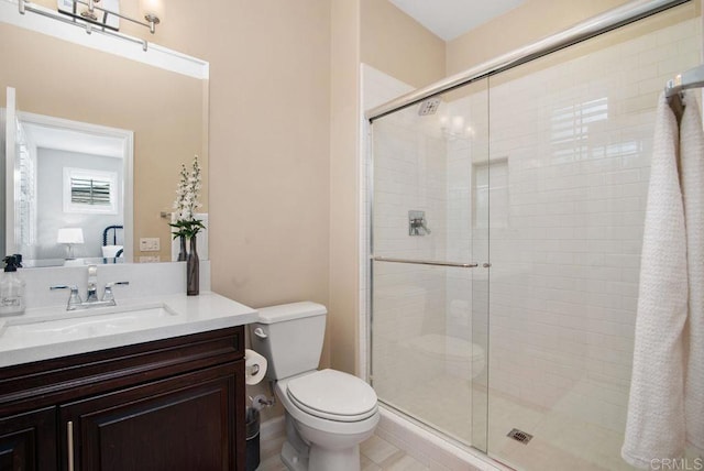 bathroom featuring vanity, a shower with door, and toilet