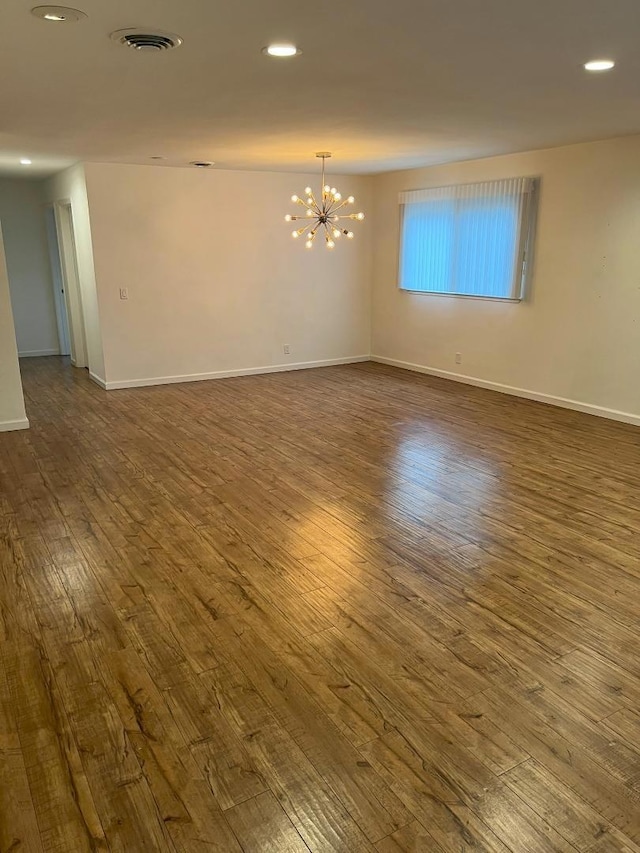 empty room featuring an inviting chandelier and dark wood-type flooring