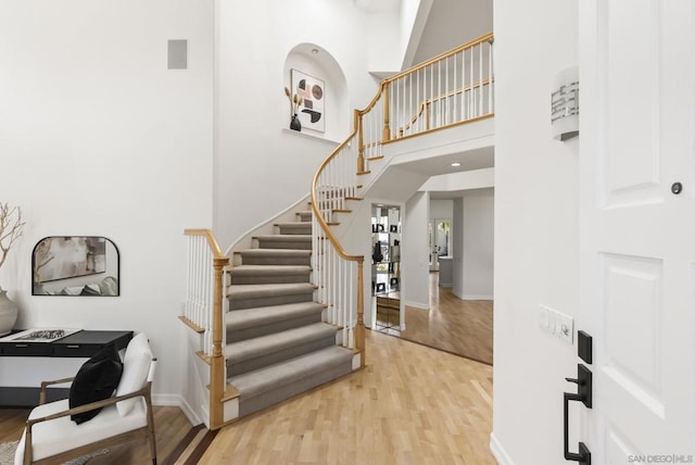 stairs featuring a towering ceiling and wood-type flooring