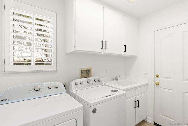 washroom with cabinets, washer and dryer, and sink