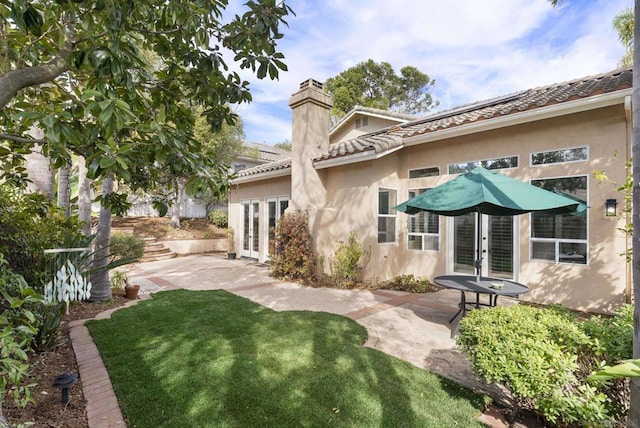 back of property featuring french doors, a yard, and a patio area