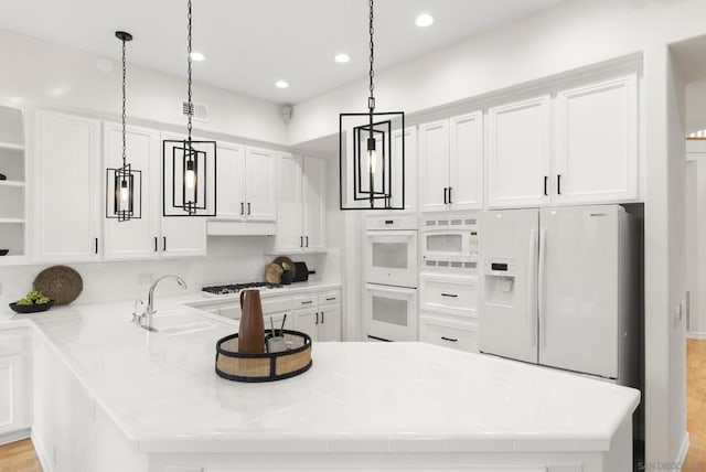 kitchen with pendant lighting, white cabinets, and white appliances