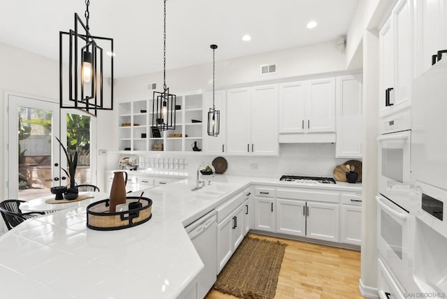 kitchen featuring sink, white appliances, decorative backsplash, white cabinets, and decorative light fixtures