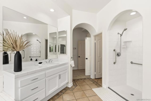 bathroom with tiled shower, tile patterned floors, and vanity