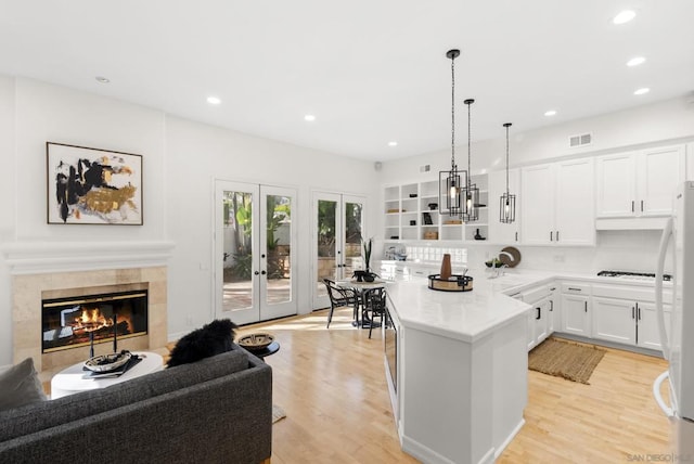 kitchen with light hardwood / wood-style flooring, white cabinets, french doors, decorative light fixtures, and kitchen peninsula