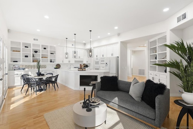 living room with sink, light hardwood / wood-style floors, and built in shelves