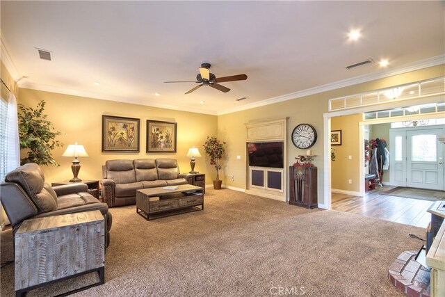 living room featuring ceiling fan, ornamental molding, and carpet flooring