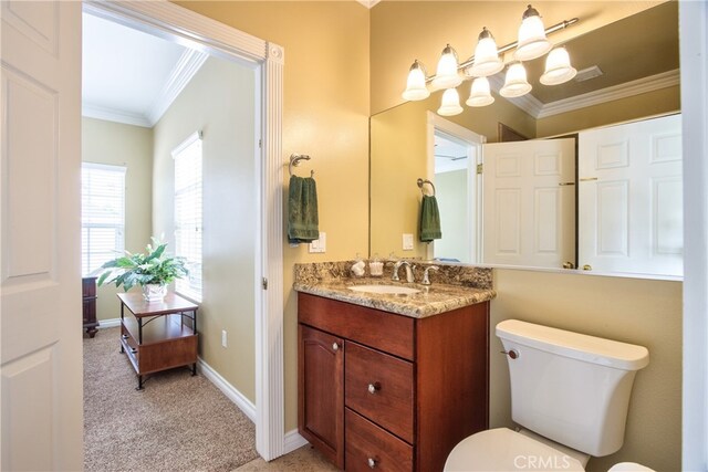 bathroom with ornamental molding, vanity, and toilet