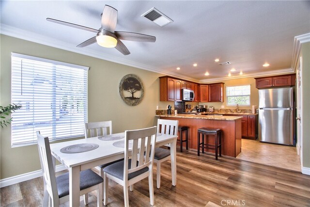 dining room with hardwood / wood-style floors, crown molding, sink, and ceiling fan