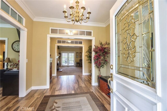 foyer entrance featuring hardwood / wood-style flooring, ornamental molding, and a chandelier