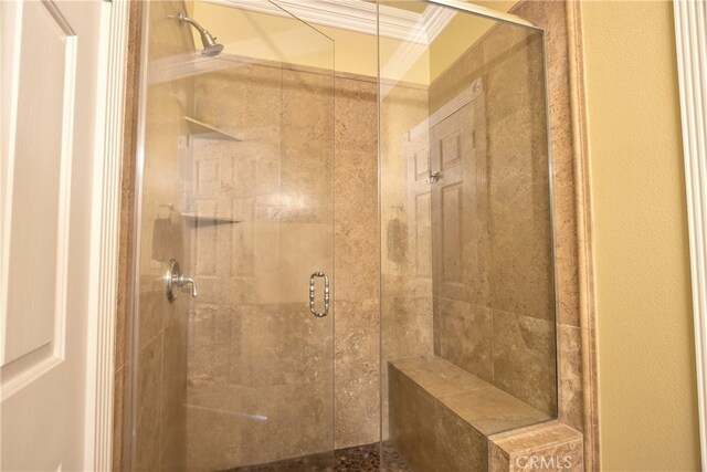 bathroom with a shower with door and ornamental molding