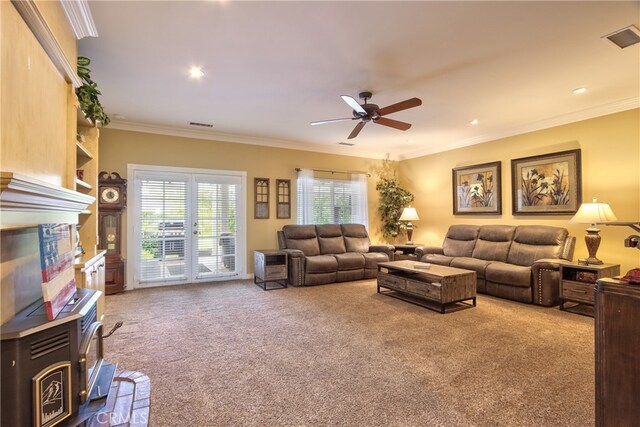 living room with crown molding, light colored carpet, ceiling fan, and a wood stove