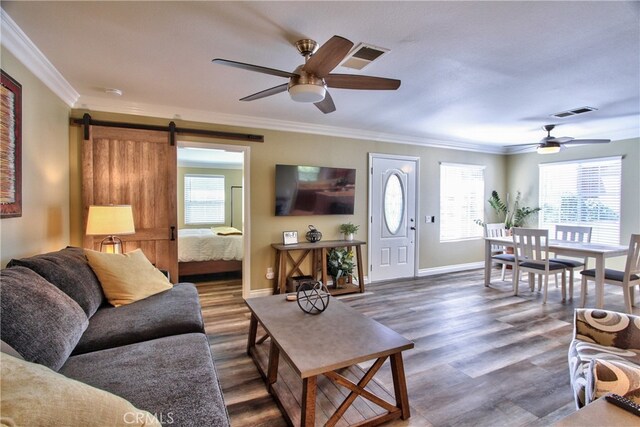 living room featuring dark hardwood / wood-style floors, crown molding, plenty of natural light, and a barn door