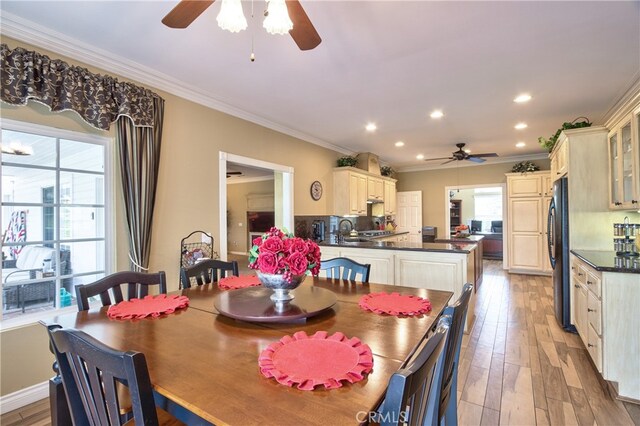 dining area with crown molding, ceiling fan, and light hardwood / wood-style floors