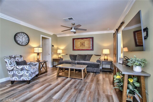 living room featuring crown molding, ceiling fan, a barn door, and hardwood / wood-style floors