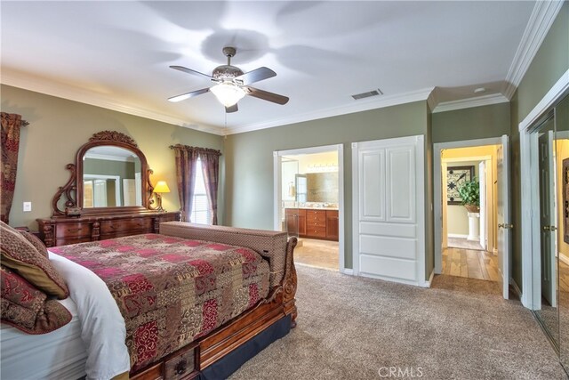 bedroom with crown molding, light colored carpet, ceiling fan, and ensuite bathroom