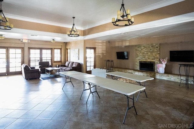 interior space with a stone fireplace, ornamental molding, a chandelier, and dark tile patterned floors