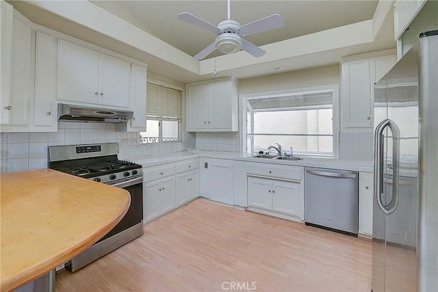 kitchen with sink, stainless steel appliances, white cabinets, decorative backsplash, and vaulted ceiling