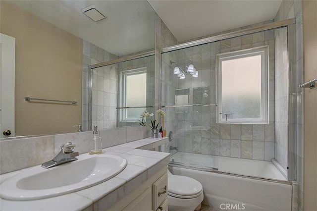 full bathroom featuring enclosed tub / shower combo, vanity, and toilet