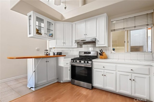 2614 Ocean Blvd, Corona Del Mar, CA 92625 - kitchen with stainless steel gas stove, under cabinet range hood, light countertops, white cabinets, and glass insert cabinets