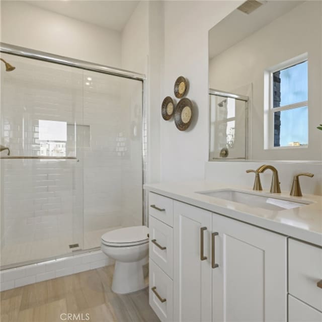 bathroom with vanity, toilet, and a shower with shower door