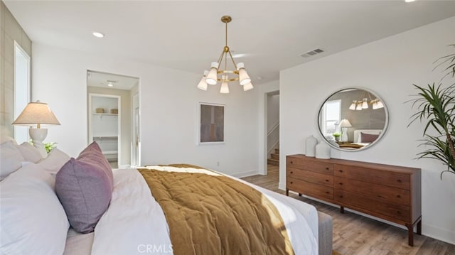 bedroom with an inviting chandelier, a spacious closet, and light hardwood / wood-style floors