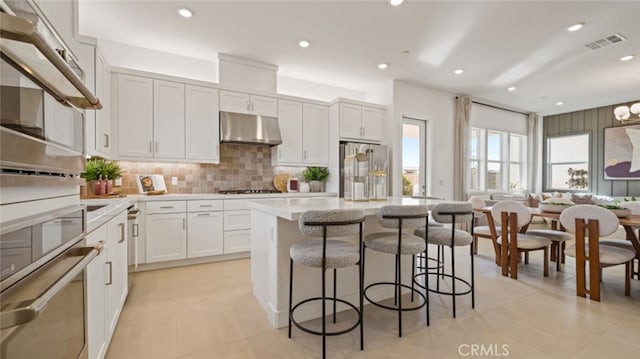 kitchen featuring backsplash, stainless steel appliances, a center island, and white cabinets