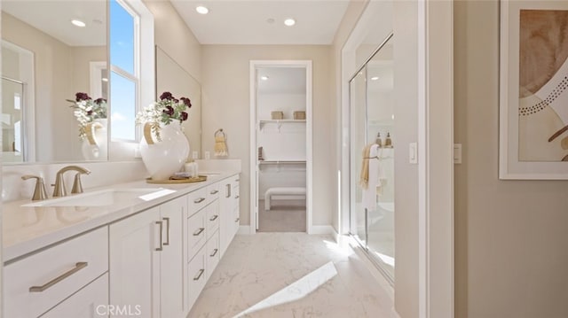 bathroom featuring a shower with door and vanity