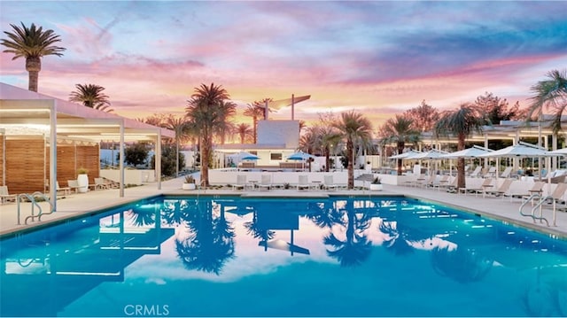 pool at dusk featuring a patio