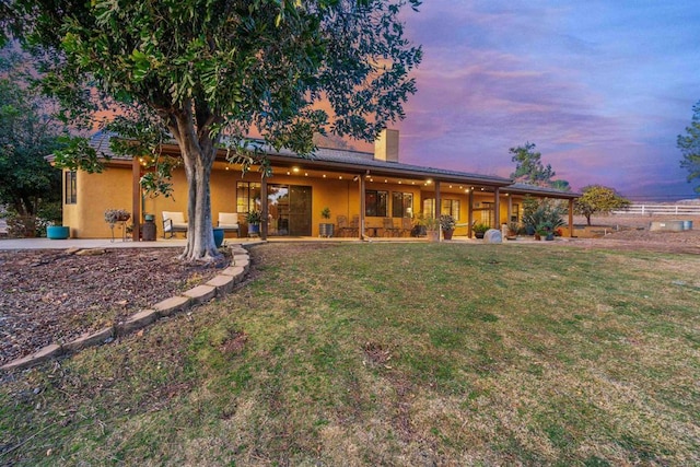 back house at dusk with a yard and a patio area