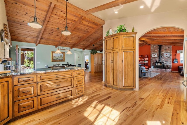 kitchen featuring vaulted ceiling with beams, a wood stove, hanging light fixtures, light hardwood / wood-style floors, and wooden ceiling