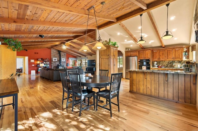 dining room with lofted ceiling with beams, a wood stove, wood ceiling, and light wood-type flooring