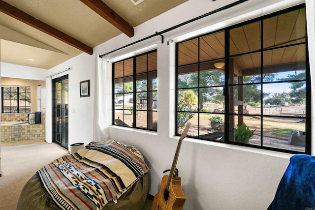 bedroom with beam ceiling, access to outside, and carpet