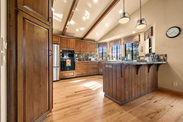 kitchen with a breakfast bar, decorative light fixtures, stainless steel fridge, kitchen peninsula, and double oven