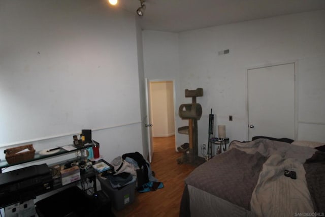 bedroom with vaulted ceiling, track lighting, and hardwood / wood-style floors