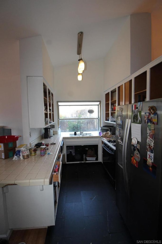 kitchen with tile countertops, white cabinetry, sink, stainless steel fridge with ice dispenser, and black range with gas cooktop