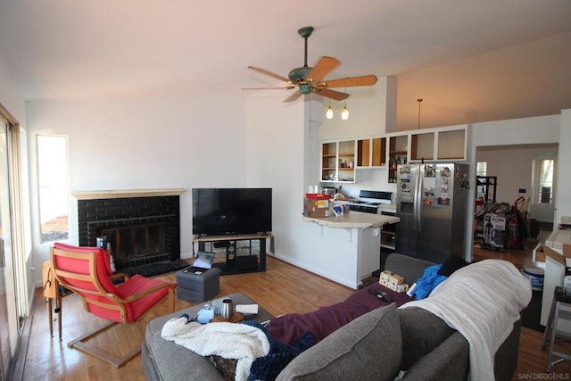 living room featuring hardwood / wood-style floors, a fireplace, ceiling fan, and vaulted ceiling