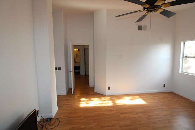 spare room with ceiling fan, a high ceiling, and light wood-type flooring