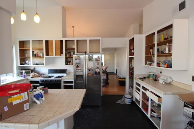 kitchen with stainless steel refrigerator with ice dispenser, tile countertops, decorative light fixtures, range with gas stovetop, and hardwood / wood-style flooring