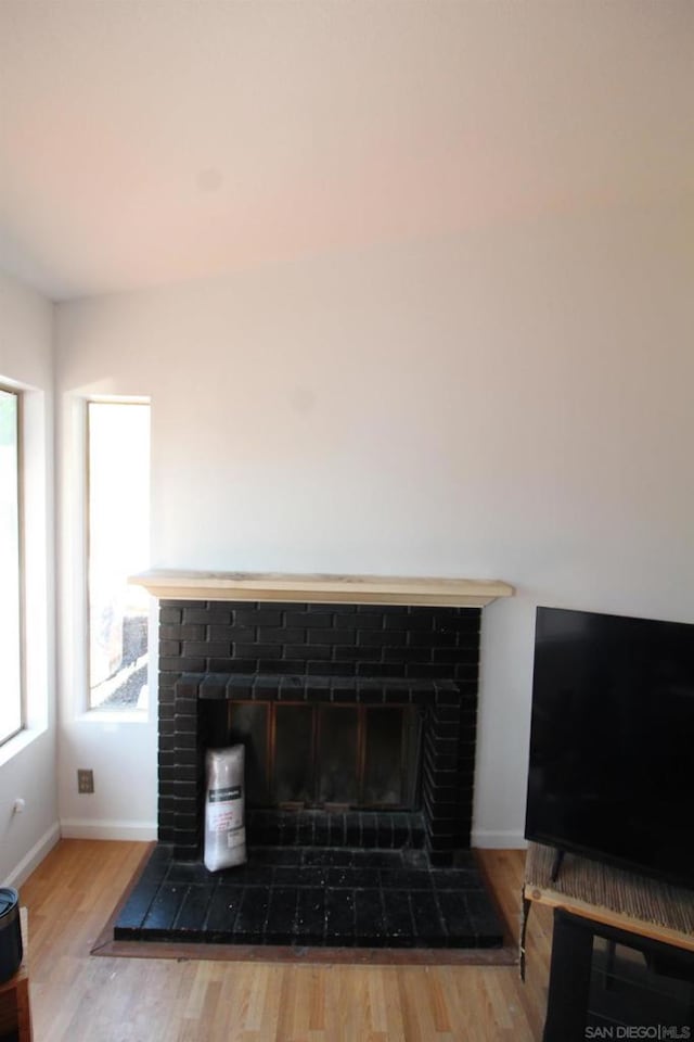 interior details featuring wood-type flooring and a brick fireplace