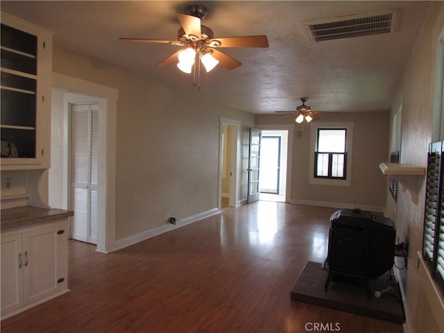 unfurnished living room with ceiling fan, light wood-type flooring, and a wood stove