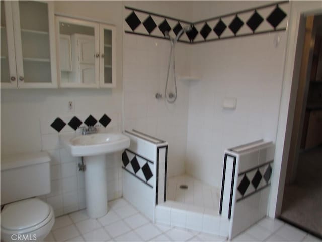 bathroom with a shower, sink, tile walls, decorative backsplash, and toilet