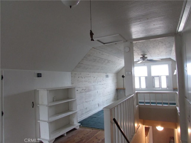 additional living space featuring lofted ceiling, hardwood / wood-style floors, ceiling fan, and wood walls