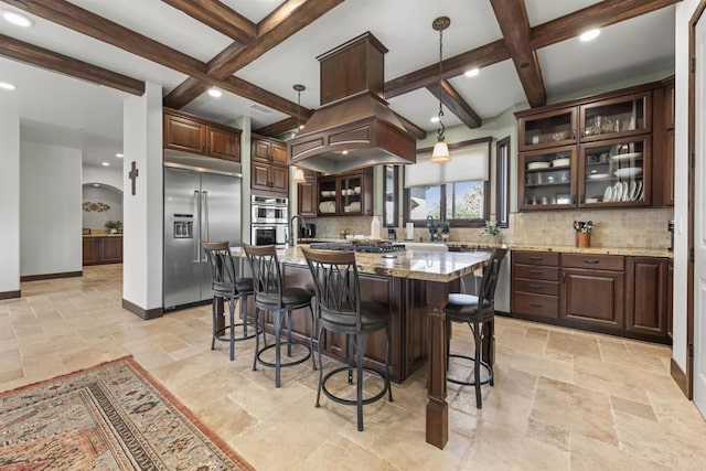 kitchen featuring light stone counters, tasteful backsplash, a center island with sink, appliances with stainless steel finishes, and pendant lighting