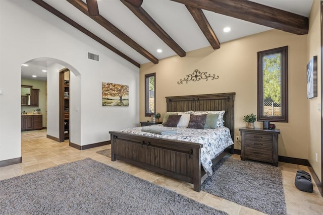 bedroom with lofted ceiling with beams and ensuite bathroom