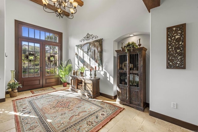 foyer entrance featuring an inviting chandelier, french doors, and a high ceiling