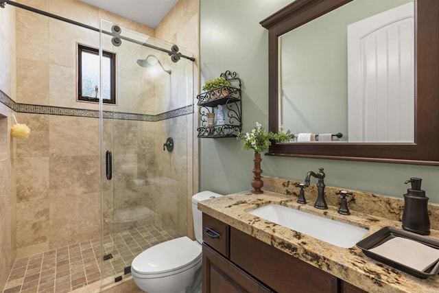 bathroom with vanity, a shower with door, and toilet